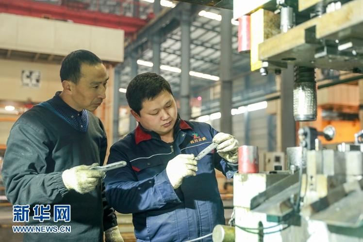 12月16日,在四川省华蓥市一家机械加工厂,工人在查看产品生产工艺.